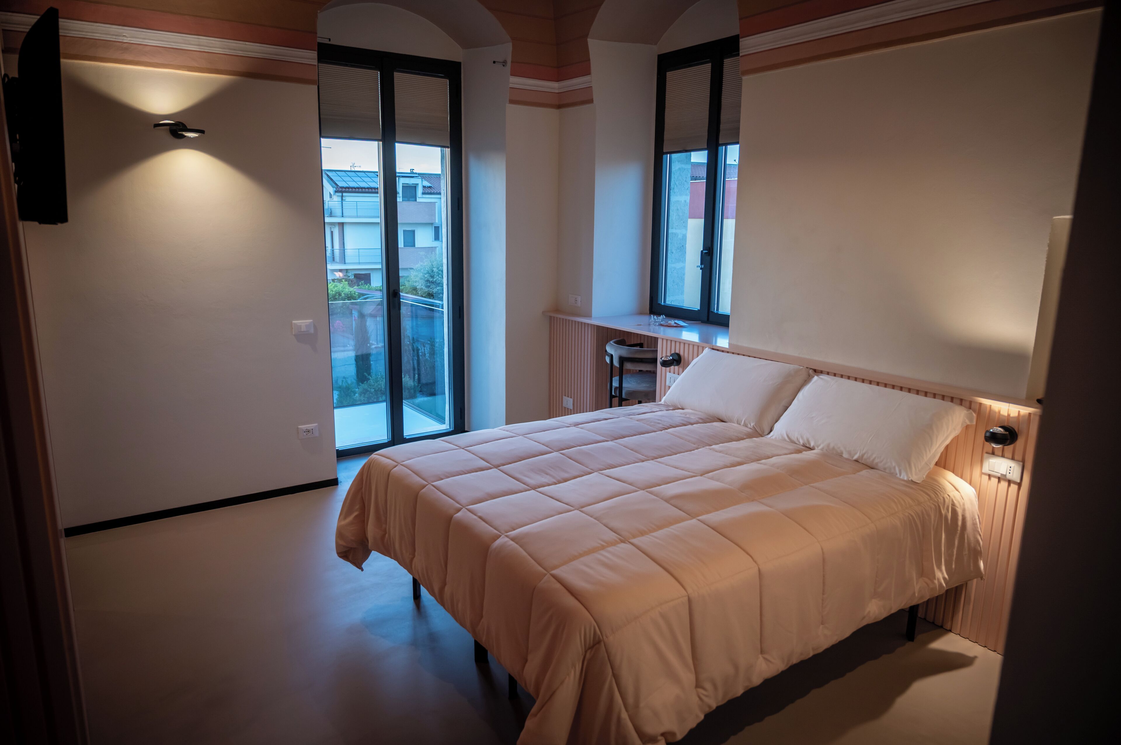 Una camera da letto con un letto, una scrivania e un'ampia finestra.