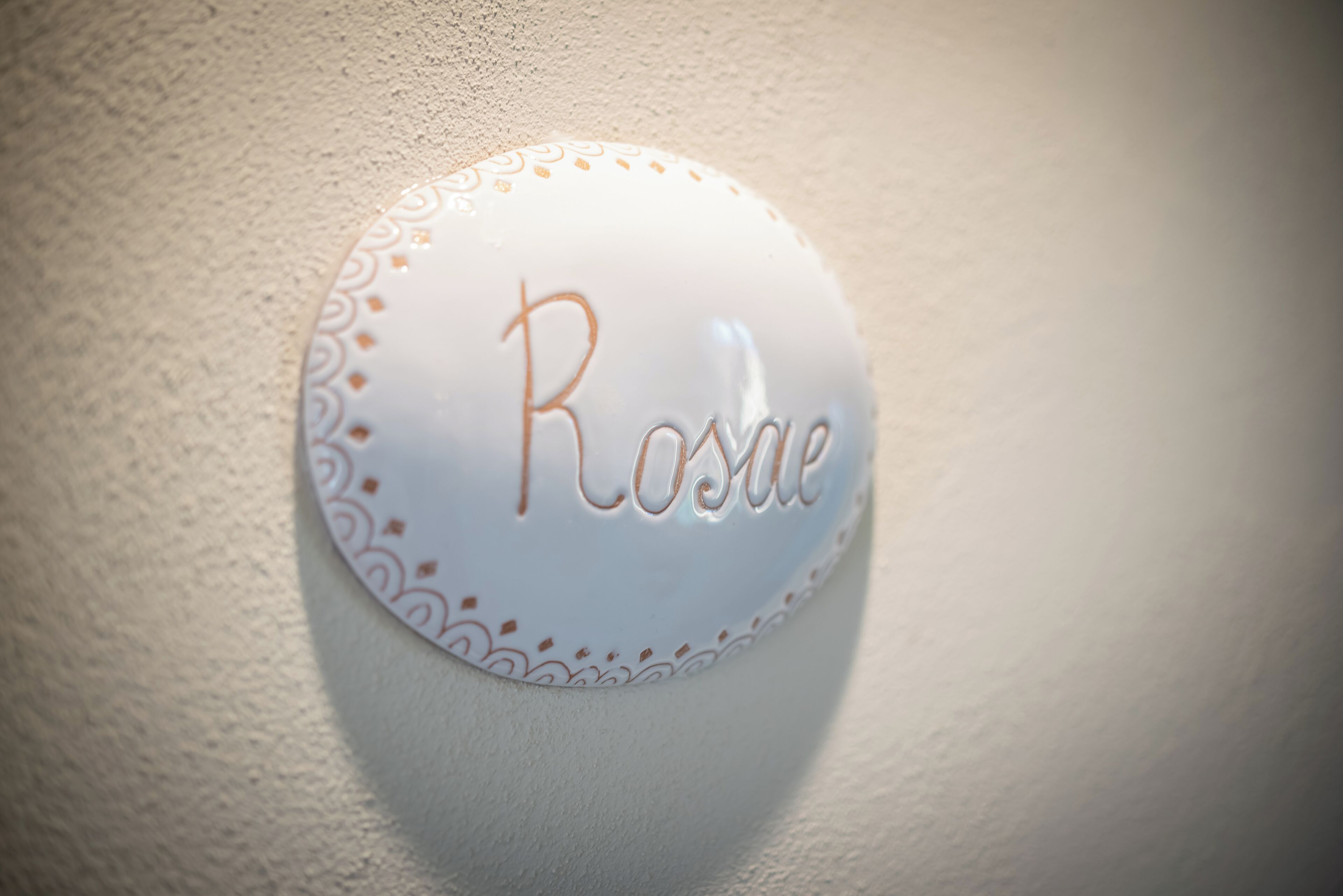 A wall-mounted sign with the name "Rosée" in cursive script.