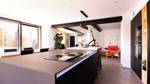 A modern kitchen with a large island, dark cabinetry, and a view to the outside.