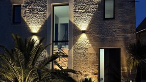 A modern house with a stone facade, large windows, and a well-lit entrance.