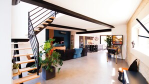 A spacious living area with a staircase, a dining area, and a kitchen in the background.