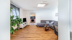 Un salon moderne avec un canapé, un téléviseur et un coin repas à l’arrière-plan.