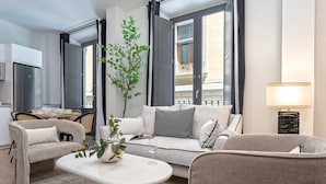 Ein modernes Wohnzimmer mit einer Couch, Sesseln, einem Couchtisch und einer Topfpflanze.