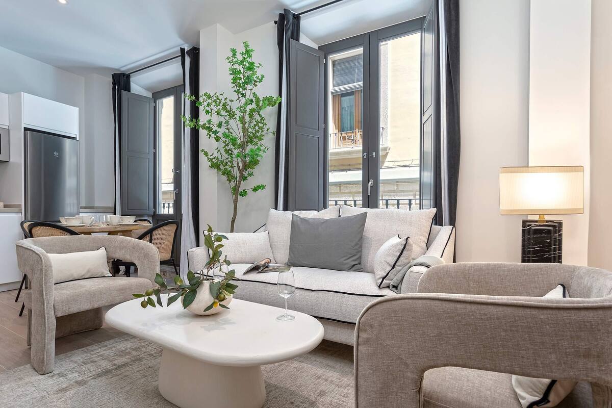 Un salon moderne avec un canapé, des fauteuils, une table basse et une plante en pot.