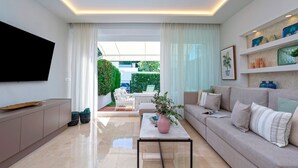 A modern living room with a sofa, coffee table, and TV. - Magnificent 3BD Duplex With Pool. Aloha Golf II (Marbella)