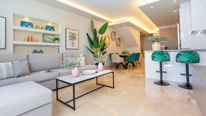 A modern living room with a sofa, coffee table, and a dining area with chairs and a table. - Magnificent 3BD Duplex With Pool. Aloha Golf II (Marbella)