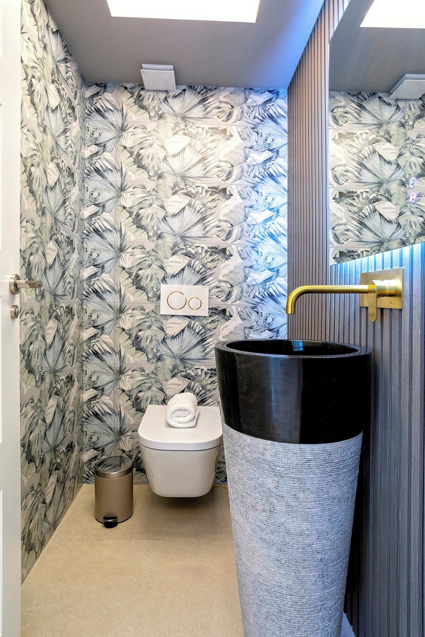A bathroom with a toilet, a black sink, and a trash can.