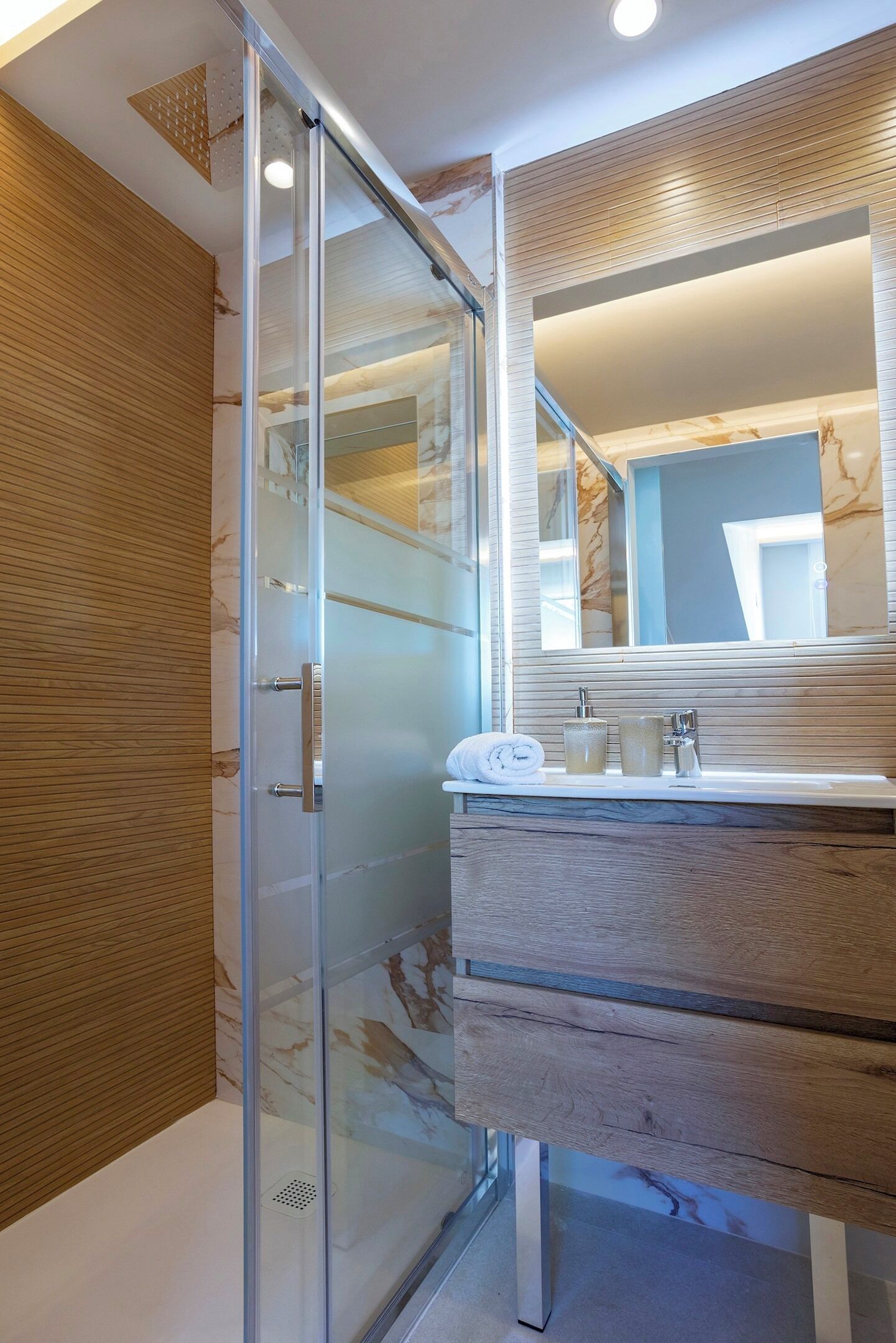 Une salle de bain moderne avec une douche à parois de verre, un meuble-lavabo en bois et un grand miroir.