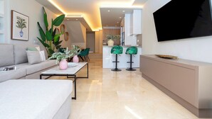 A modern living room with a sofa, coffee table, and a TV mounted on the wall. - Magnificent 3BD Duplex With Pool. Aloha Golf II (Marbella)