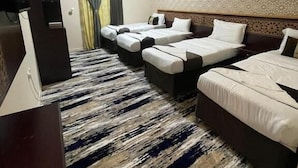 A hotel room with three beds, a television, and a patterned carpet. - Al Resala Al Masi Hotel (Makkah)