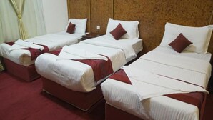 A hotel room with three single beds, each with a red accent pillow and white bedding. - Al Resala Al Masi Hotel (Makkah)