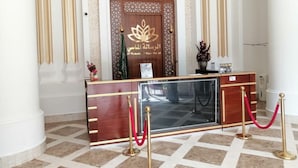 A reception desk with a wooden finish, glass partition, and gold accents. - Al Resala Al Masi Hotel (Makkah)