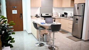 A modern kitchen with a central island, stainless steel appliances, and bar stools. - Premium Suite at The Vineyards (Kingston)