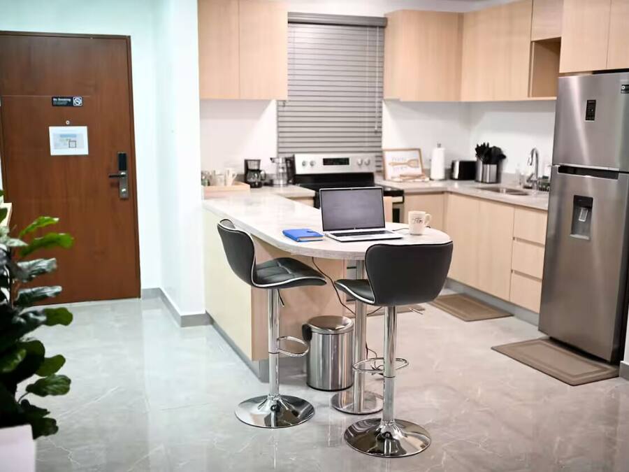 A modern kitchen with a central island, stainless steel appliances, and bar stools.