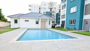 A modern residential building with a swimming pool, a covered patio, and a well-maintained lawn. - Premium Suite at The Vineyards (Kingston)