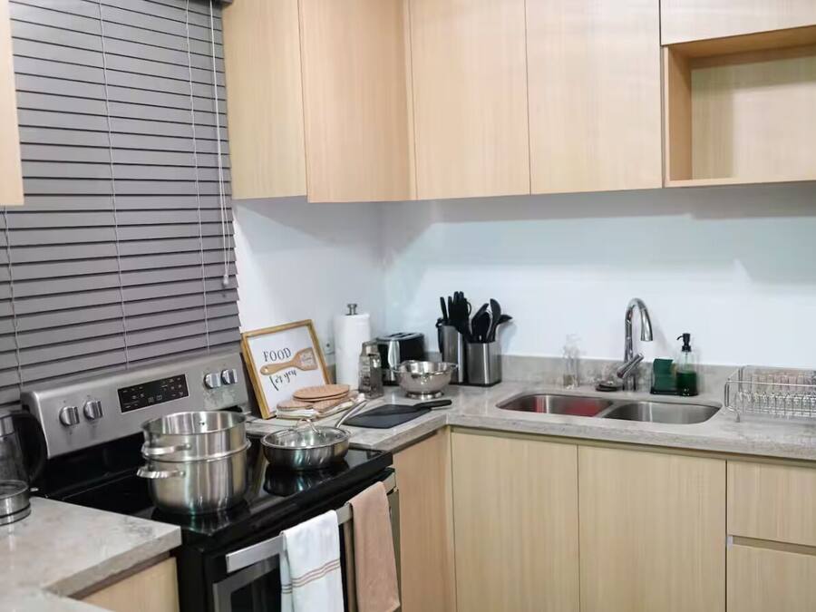 A kitchen with wooden cabinets, a stove, a sink, and various kitchen utensils.