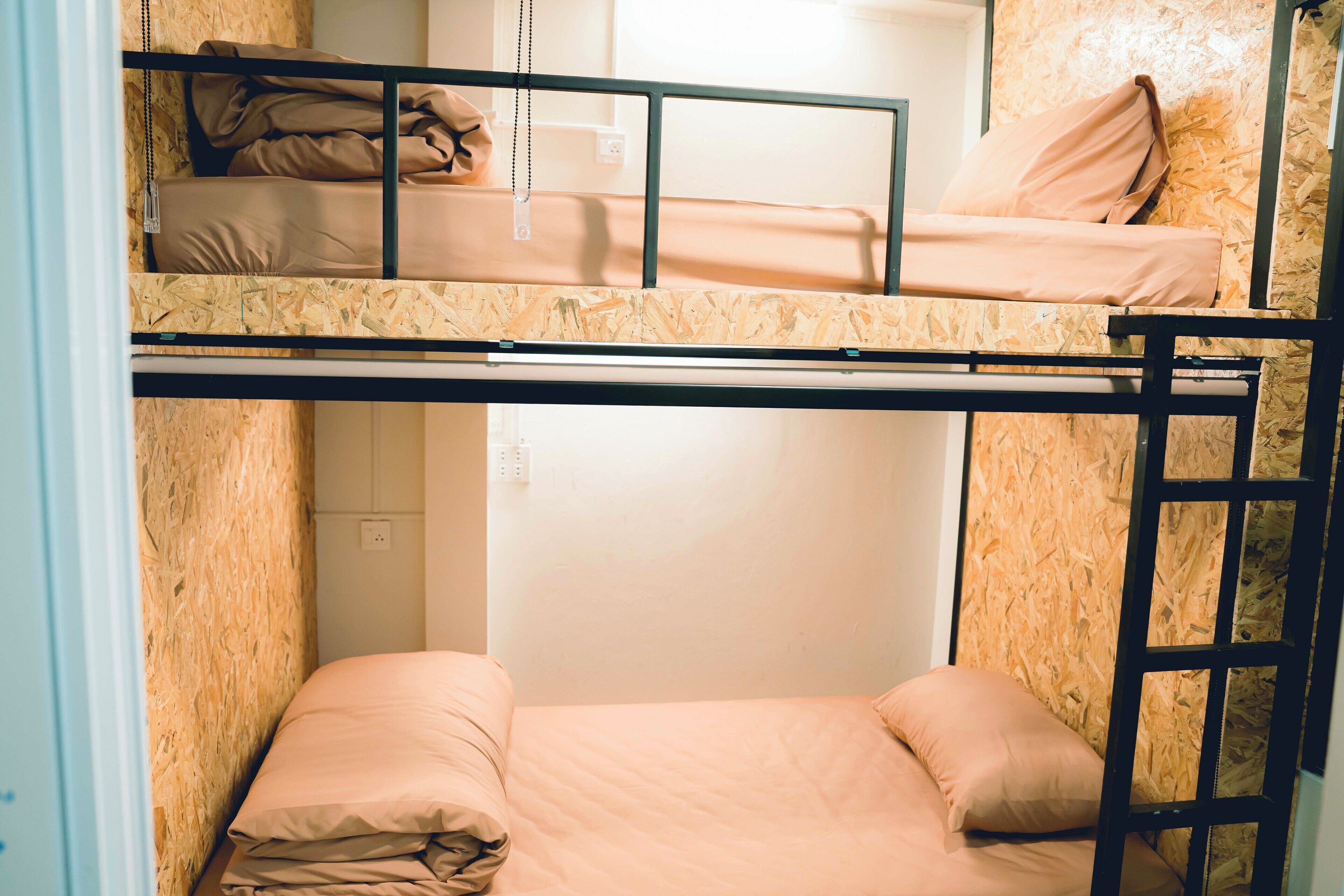 A bunk bed room with two levels, wooden walls, and a white door.
