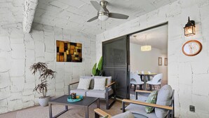 A modern living room with a sofa, chairs, a coffee table, and a potted plant.