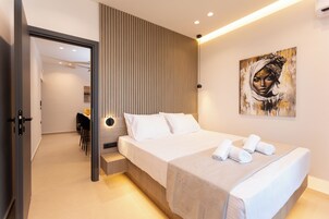 Un hotel moderno con una cama grande, una mesita de noche, una obra de arte en la pared y vistas al área de comedor contigua.
