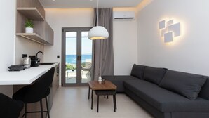 Un salon moderne avec un canapé gris, une petite table en bois et un coin cuisine doté d’un plan de travail blanc.