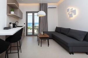 Una sala moderna con un sofá gris, una mesita de madera y una cocina con encimera blanca.