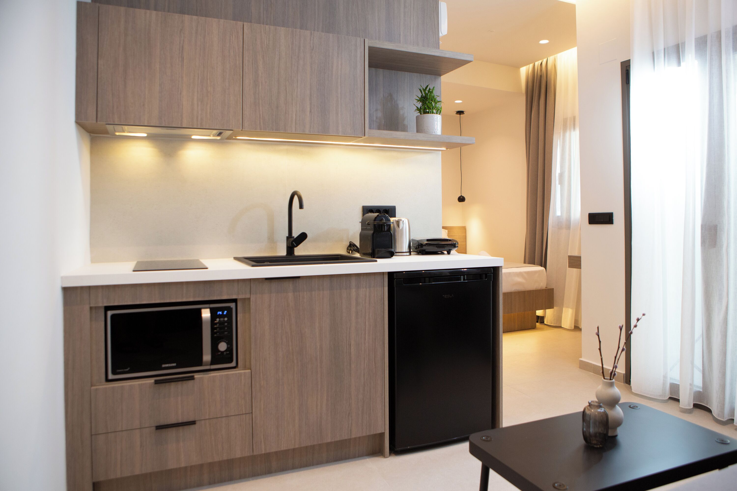 Una cocina moderna con electrodomésticos integrados, un comedor y vistas al dormitorio.