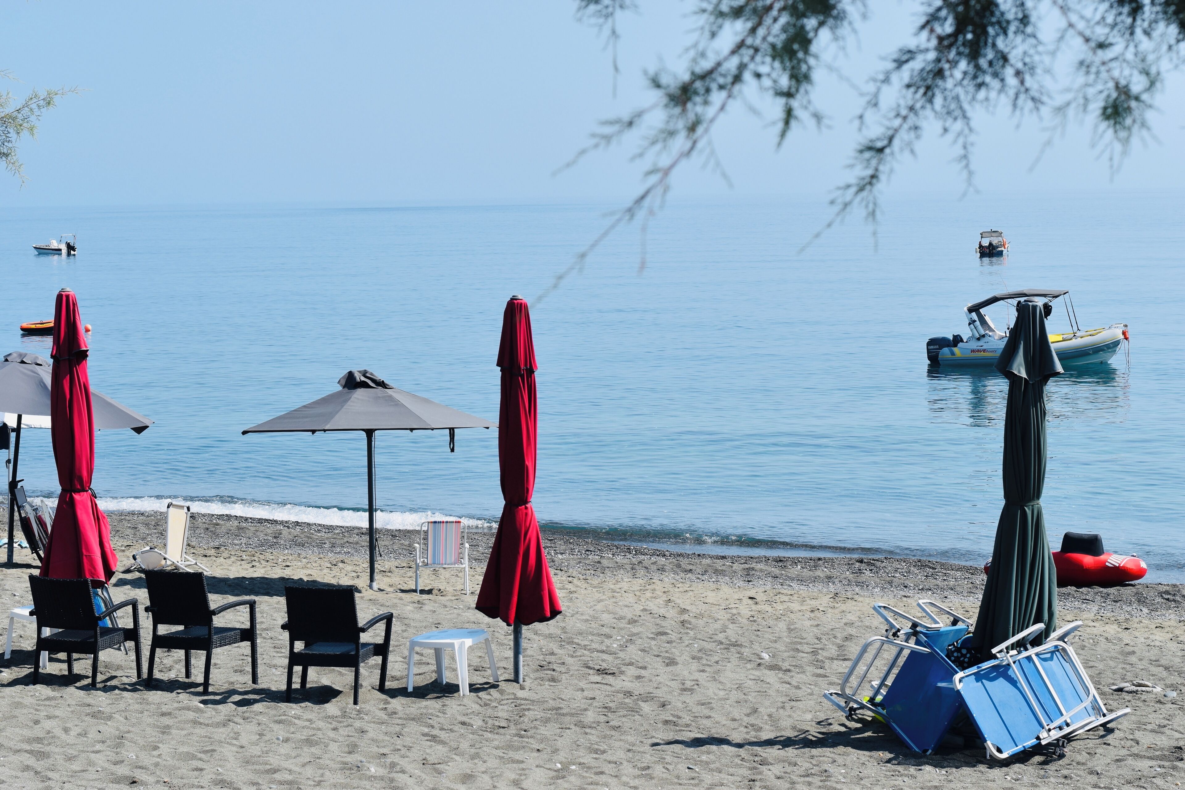 A beach with umbrellas, chairs, and a boat in the water.