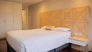 A modern bedroom with a large bed, a wooden headboard, a bedside table, and a wardrobe. - Sophisticated 1BR Stay in Prime Miraflores (Lima)