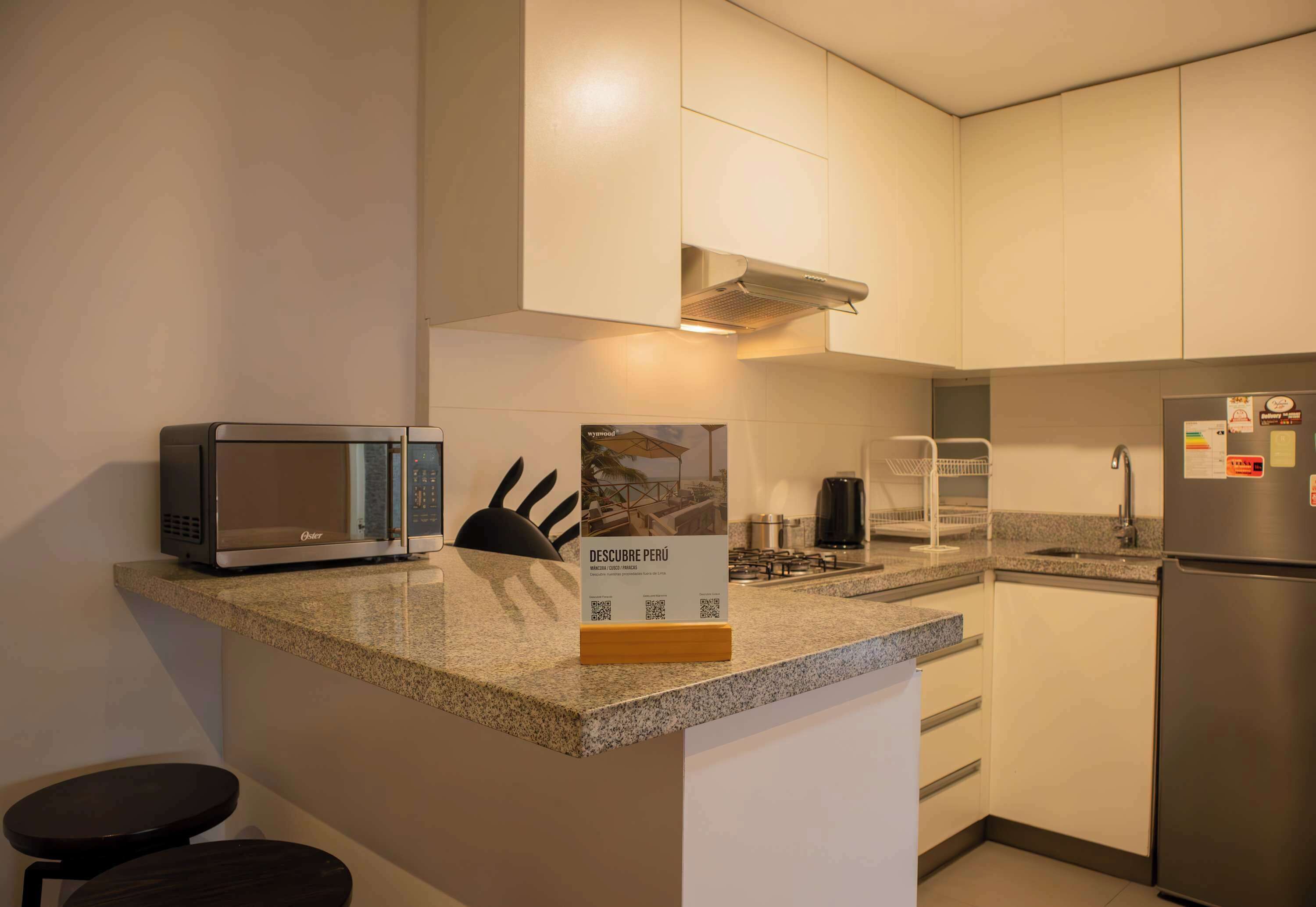 A modern kitchen with a built-in microwave, a gas stove, and a stainless steel refrigerator.