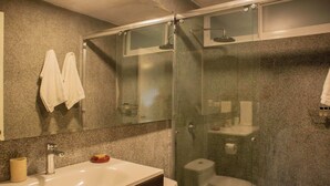 A bathroom with a glass-enclosed shower, a sink with a mirror above it, and a toilet. - Sophisticated 1BR Stay in Prime Miraflores (Lima)