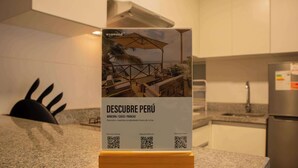 A kitchen counter with a sign advertising 'Descubre Perú' properties in Mancora, Cusco, and Paracas. - Sophisticated 1BR Stay in Prime Miraflores (Lima)
