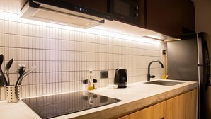 A kitchen with a black induction cooktop, a built-in oven, a microwave, and a refrigerator. - w Scenic 1BR w Terrace in Barranco (Lima)