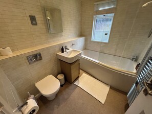 Une salle de bain avec des toilettes, un lavabo et une baignoire.