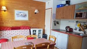 Une cuisine chaleureuse avec des meubles en bois, une table à manger avec des chaises et un four à micro-ondes.