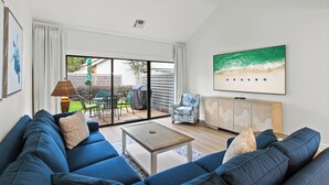 Een moderne woonkamer met een grote bank, een salontafel en een aan de muur bevestigde televisie.