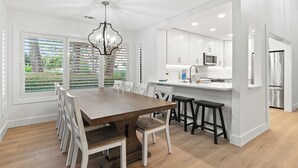 Een moderne keuken met witte kastjes, een houten eettafel en een kroonluchter.