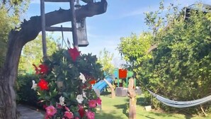 A garden with a tree, pink flower pots, and a hammock. - Laboratorio Gourmet (Taormina)