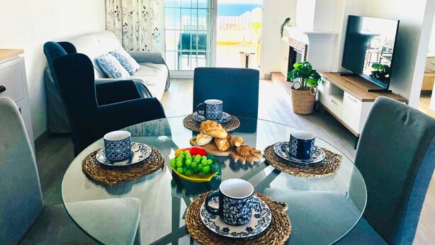Un salon moderne comprenant un canapé, deux fauteuils, une table basse en verre et un téléviseur.