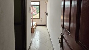 Un couloir avec une porte en bois, un lit et une fenêtre donnant sur un paysage verdoyant.