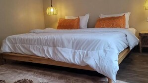 Une chambre à coucher avec un lit, deux lampes de chevet, un tableau encadré au mur et un tapis à motifs.