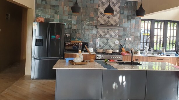 Une cuisine moderne dotée d’un îlot central, d’appareils électroménagers en acier inoxydable et d’un revêtement mural décoratif.