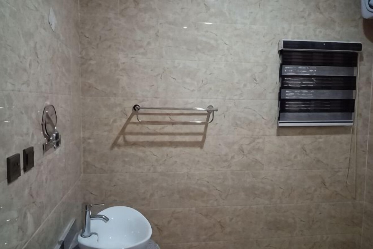 A bathroom with a sink, mirror, towel rack, and a shower area.