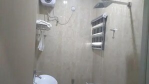 A bathroom with a toilet, a sink, a towel rack, a soap dispenser, and a shower head. - Mozida Suites  (Kano)