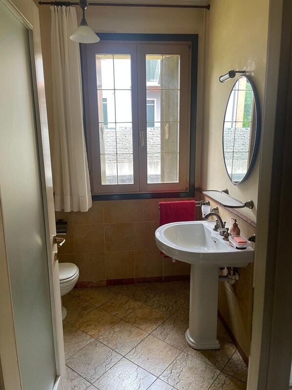 Un baño con inodoro, lavamanos y ventana.