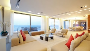 Un salon moderne comprenant un grand canapé, une table basse et un coin repas avec des chaises et une table.