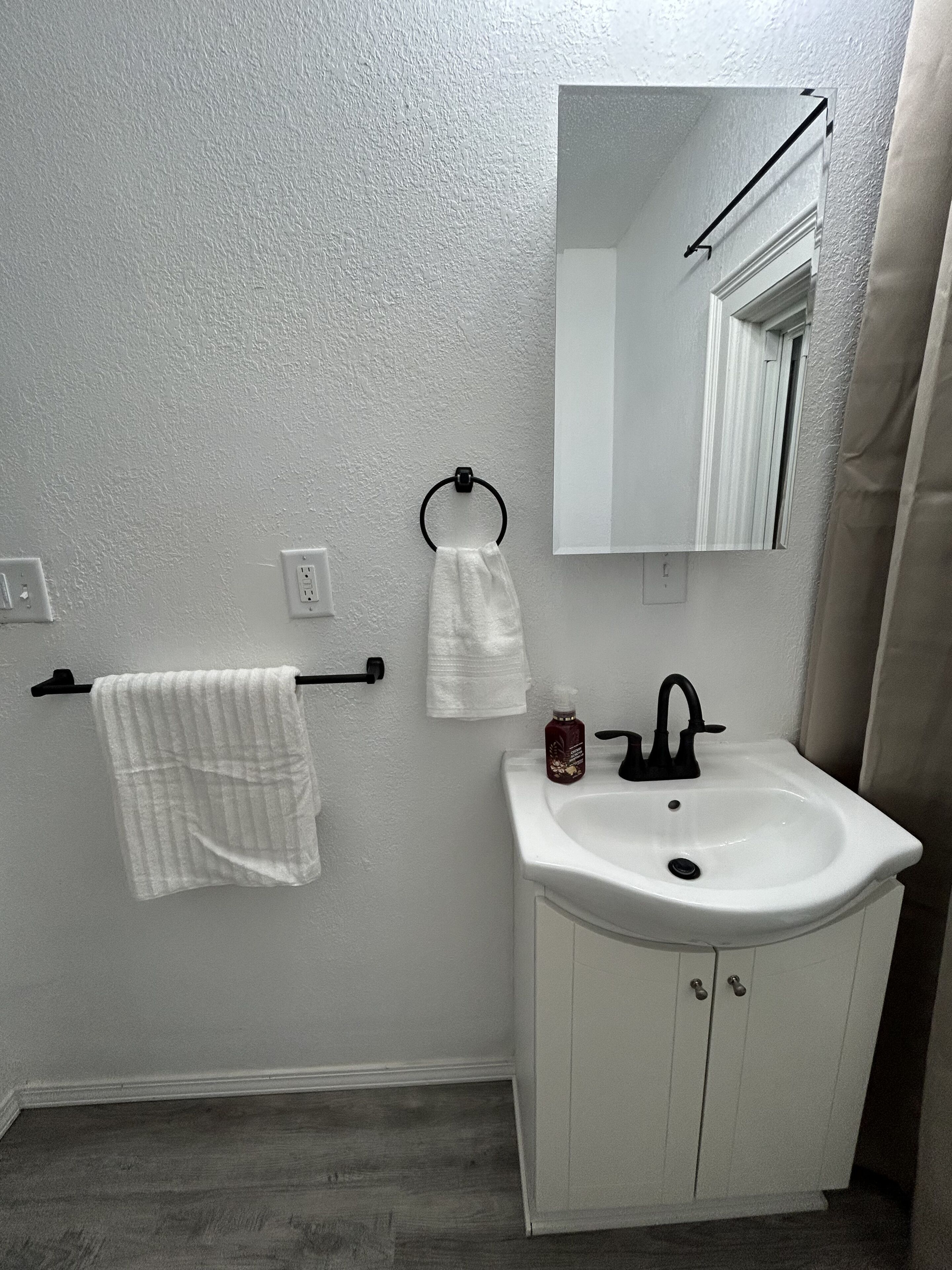 A bathroom with a white sink, a mirror, and a towel rack.