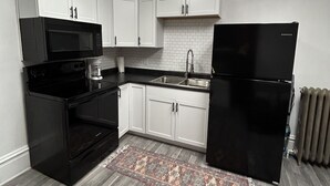 A modern kitchen with white cabinets, a black refrigerator, a microwave, and a coffee maker.