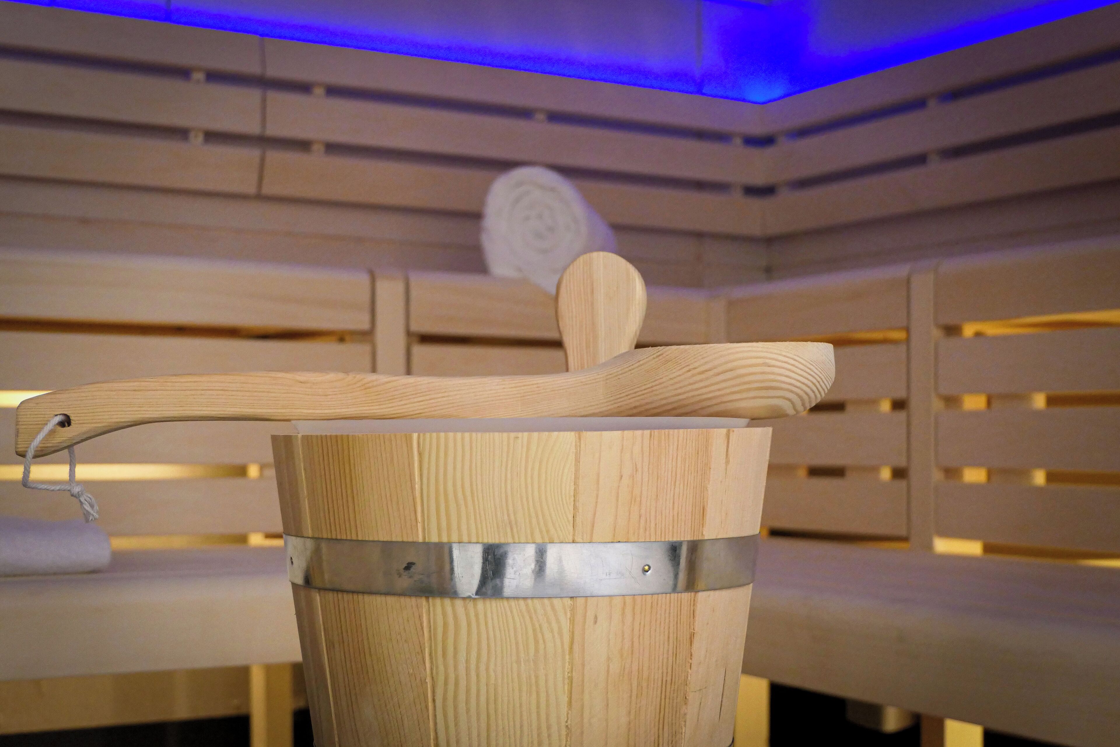 A sauna with wooden benches and a metal bucket.