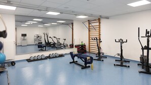 A gym with exercise equipment, a mirror, and a blue floor. - Sporthotel Treff Punkt (Wiesbaden)