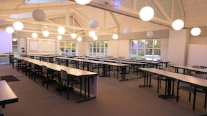 A spacious conference room with long tables and chairs, large windows, and hanging spherical lights. - Sporthotel Treff Punkt (Wiesbaden)
